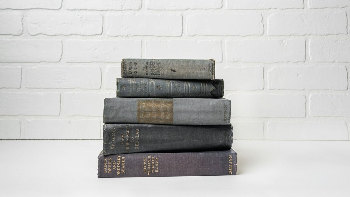 Стос старих книжок біля білої цегляної стіни